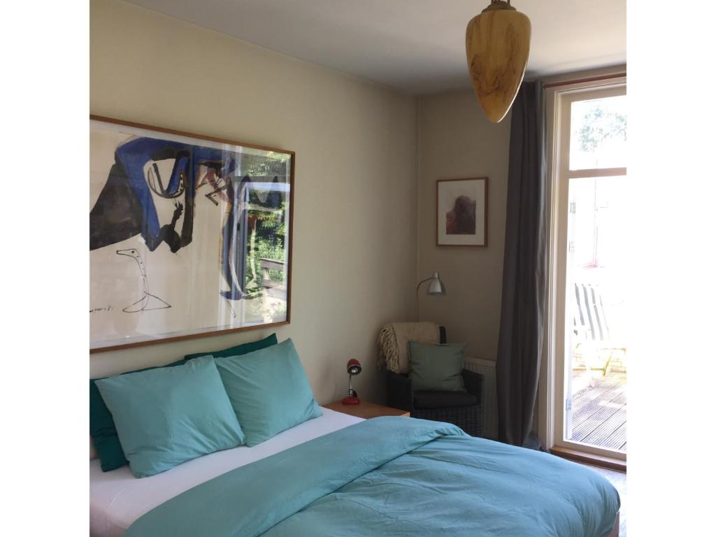 海牙Bed & Breakfast Leonie的一间卧室配有一张带蓝色床单的床和一扇窗户。
