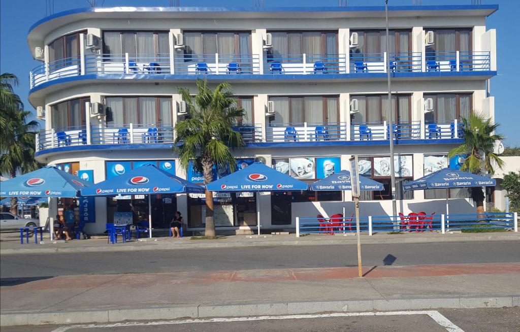 阿纳克利亚Hotel Cruise的前面有蓝色伞的建筑