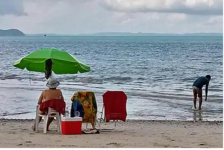伊塔帕里卡Casa Ilha de Itaparica的两人坐在海滩上,被一把绿色伞所环绕
