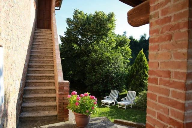 锡耶纳“Il Nespolino” Tuscan Country House的天井设有两把椅子和花盆,楼梯