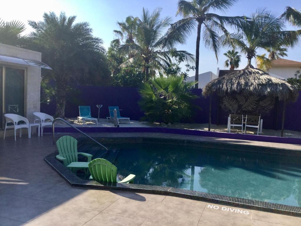 棕榈滩Sandcastle Beach Apartments的一个带椅子和桌子的游泳池,并种植了棕榈树