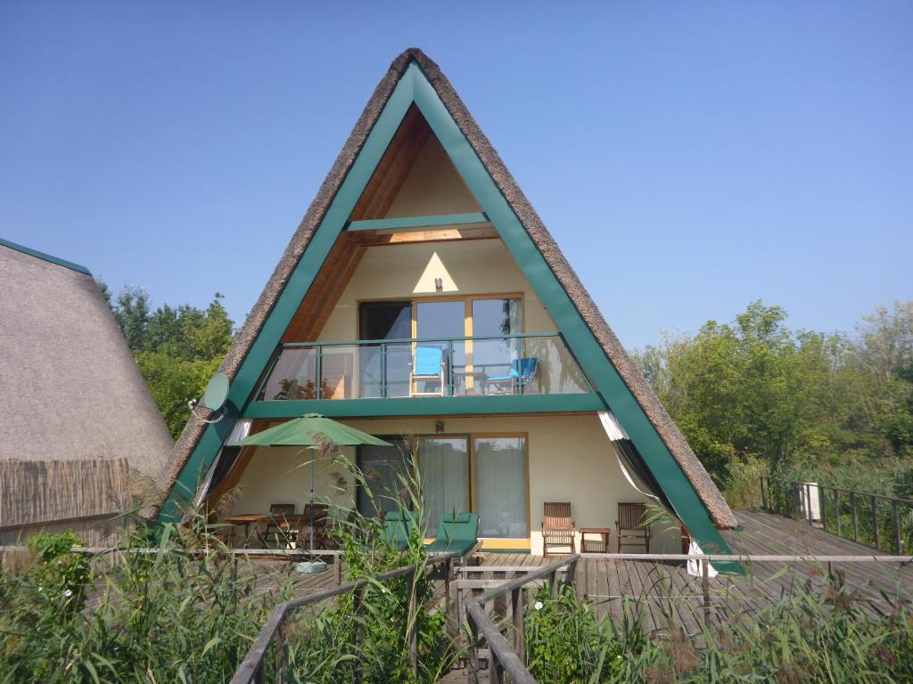 新锡德勒湖畔普巴赫Ferienhäuser Finiki的带阳台的茅草屋顶房屋