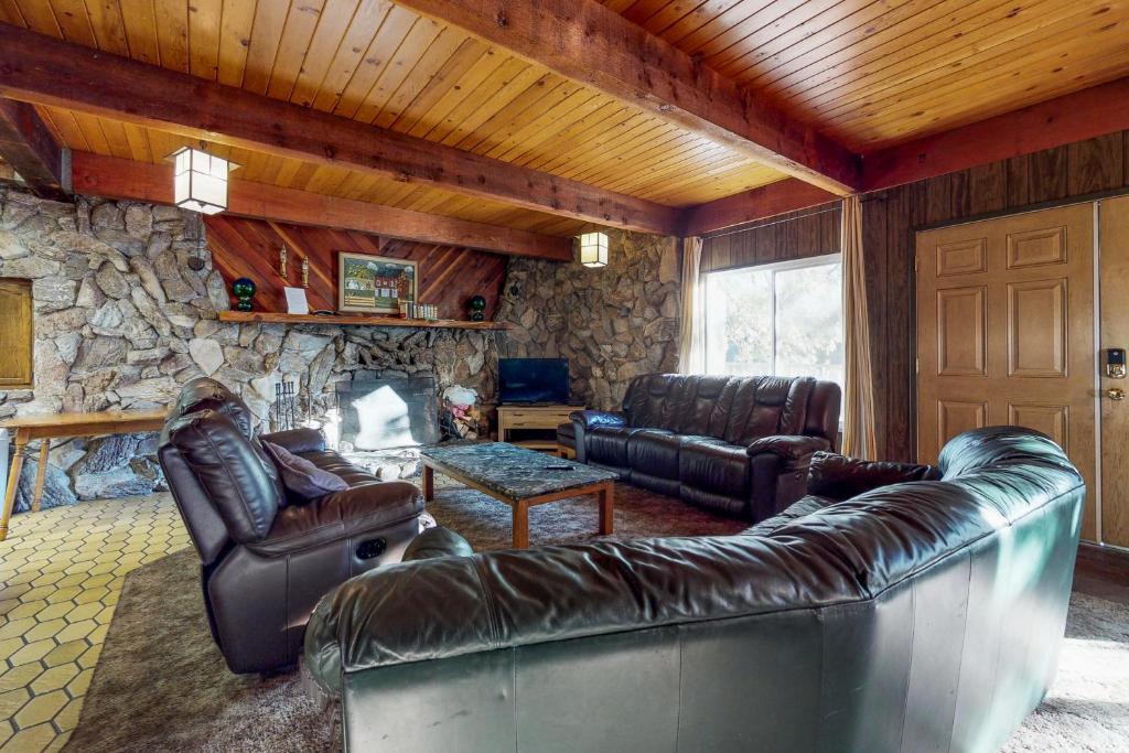 谢弗湖Pond View Lodge的客厅配有皮革家具和石墙