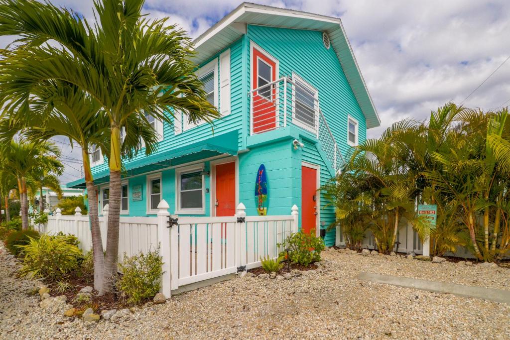 布雷登顿海滩Bay View Inn 202的蓝色的房子,有白色的围栏和棕榈树