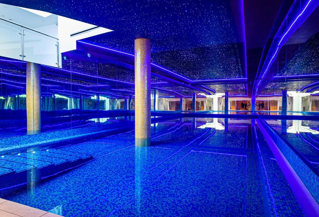 希灵登Atrium Hotel Heathrow的紫色照明的建筑中的游泳池