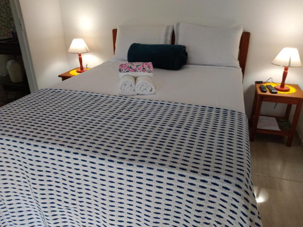 帕拉蒂Chalés Vale dos Pássaros的一间卧室配有一张带两盏灯的大型白色床。