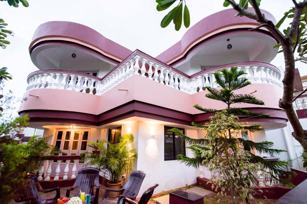 比纳里姆'Golden Sunset' 3bhk beach villa的粉红色的房子设有阳台和树木