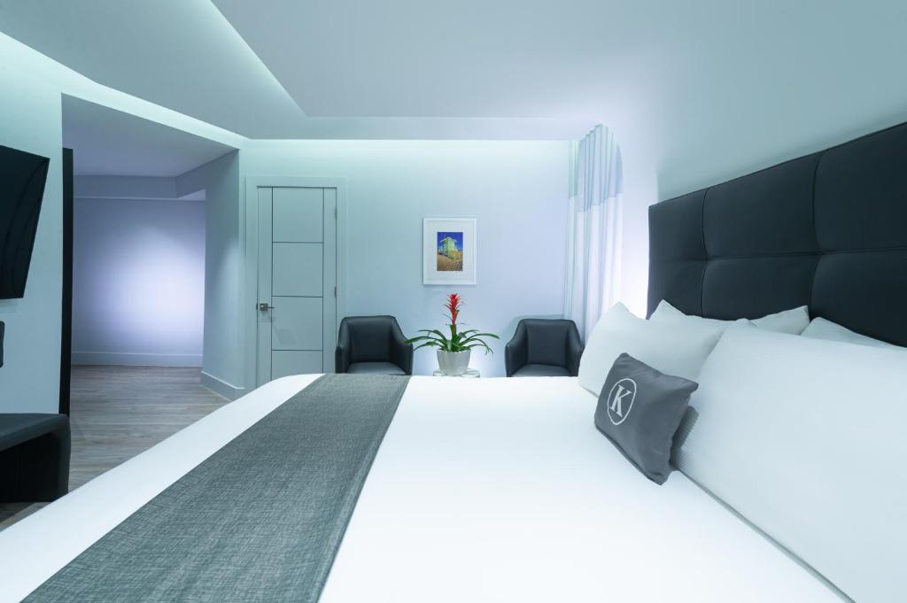 迈阿密海滩肯特酒店的一间卧室配有一张白色大床和黑色床头板