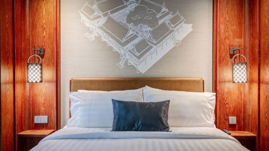 曼谷斯考酒店的一间卧室配有一张带木制床头板的床
