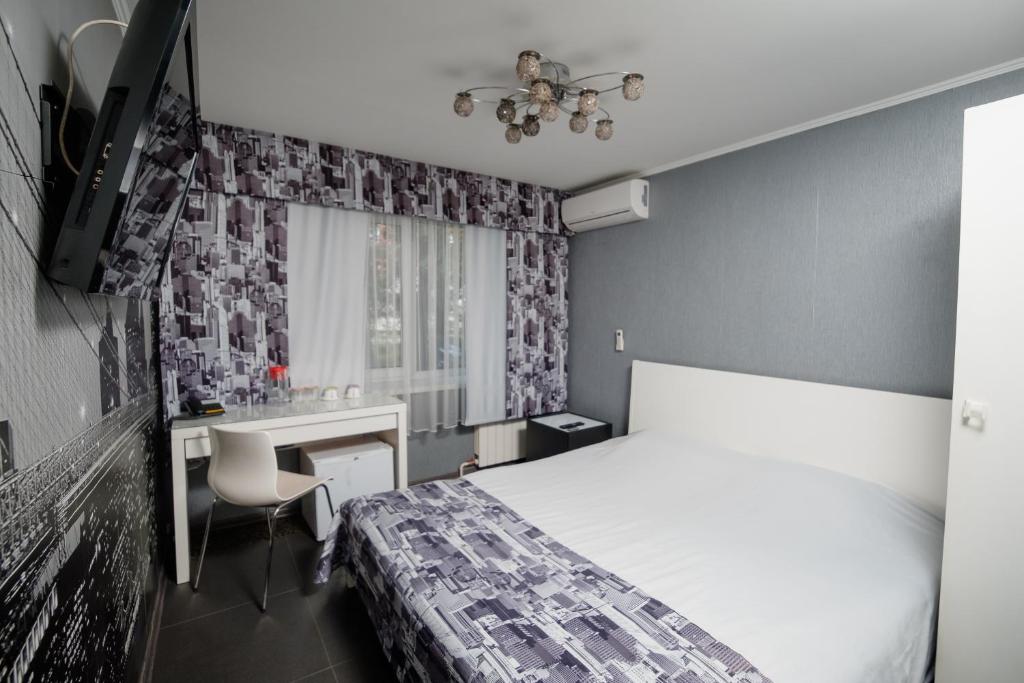新库兹涅茨克Aurooms的一间卧室配有一张床、一张书桌和一个窗户。