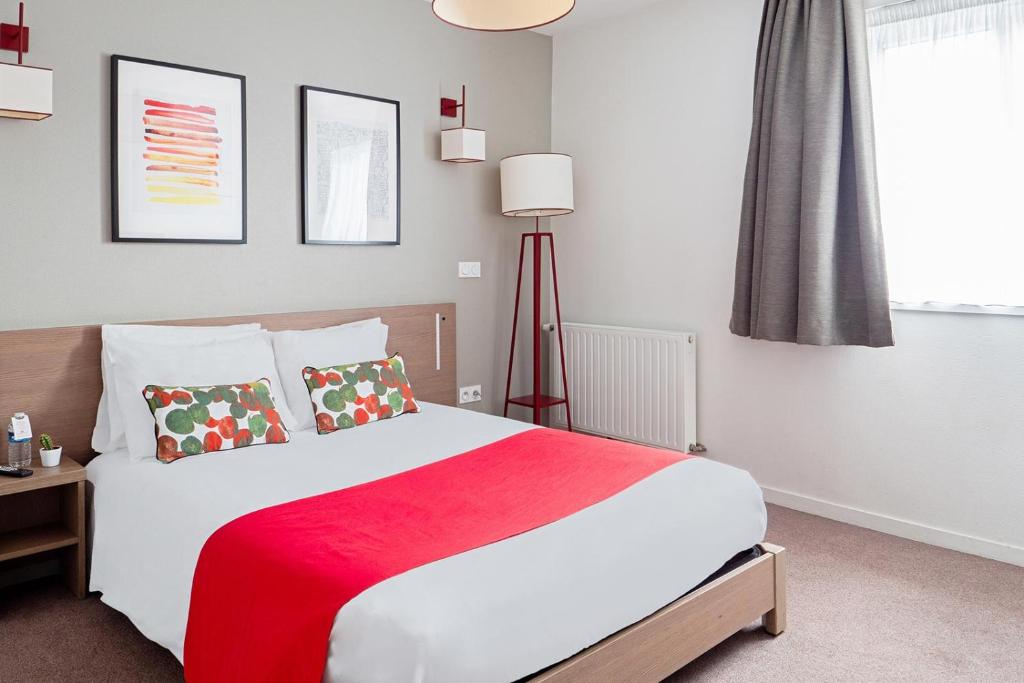 奥尔良Appart'City Confort Orléans的一间卧室配有一张带红色毯子的大床