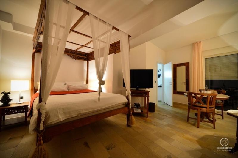 萨尔布吕肯雷汀戈尔庄园酒店的一间卧室配有一张天蓬床、一张桌子和一台电视机