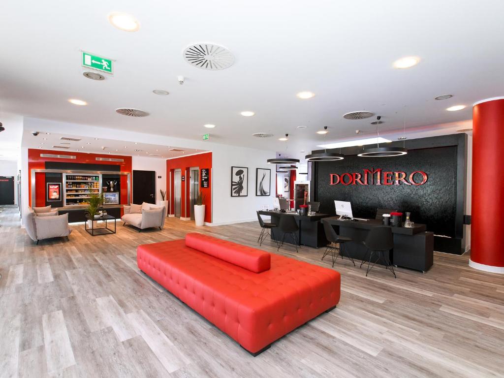 格拉特布鲁格DORMERO Hotel Zürich Airport的一间带红色沙发的客厅和一间餐厅