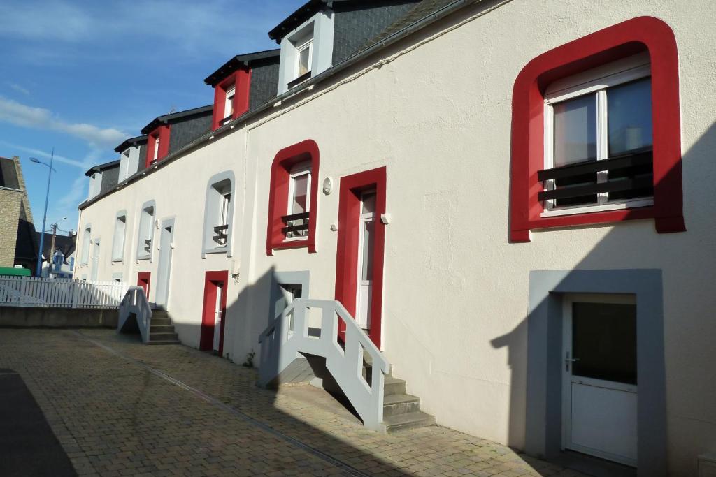 克罗宗Appartement Fontaine Morgat的白色的建筑,有红色的窗户和楼梯