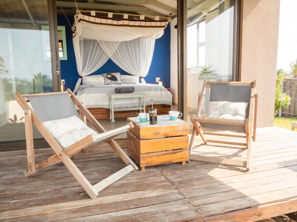 托弗海滩Casa Narinho的一间卧室,在甲板上配有一张床和两把椅子