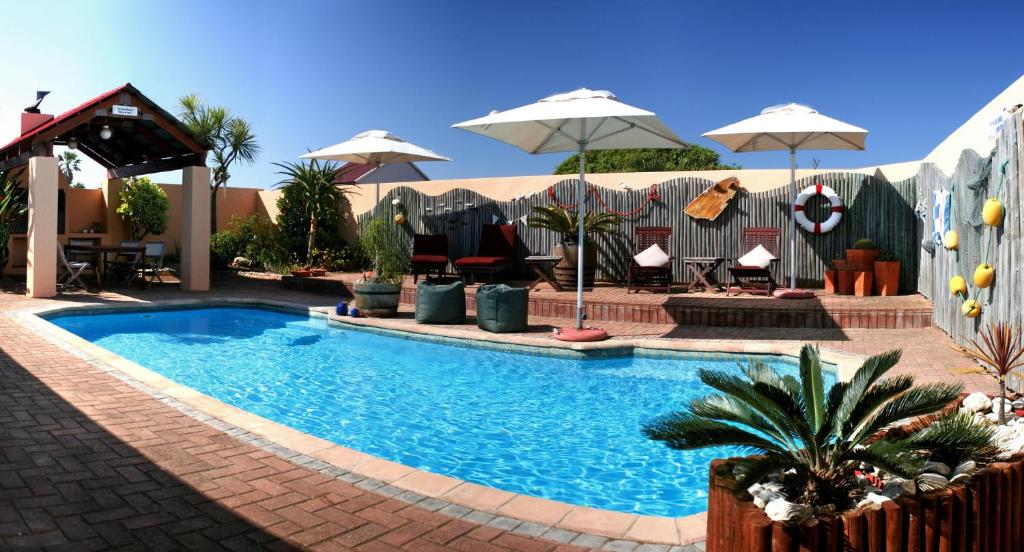 莫塞尔湾Avenues Guesthouse的一个带遮阳伞和桌椅的游泳池