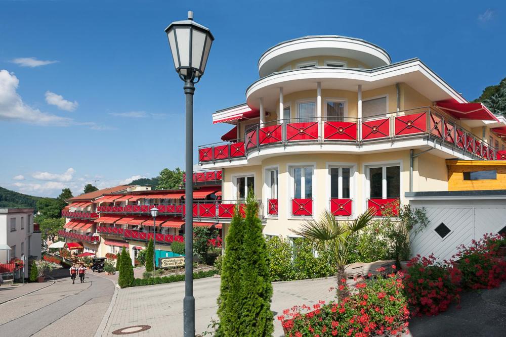 巴登韦勒后温泉健康私人酒店的白色的建筑,设有红色的阳台和街灯