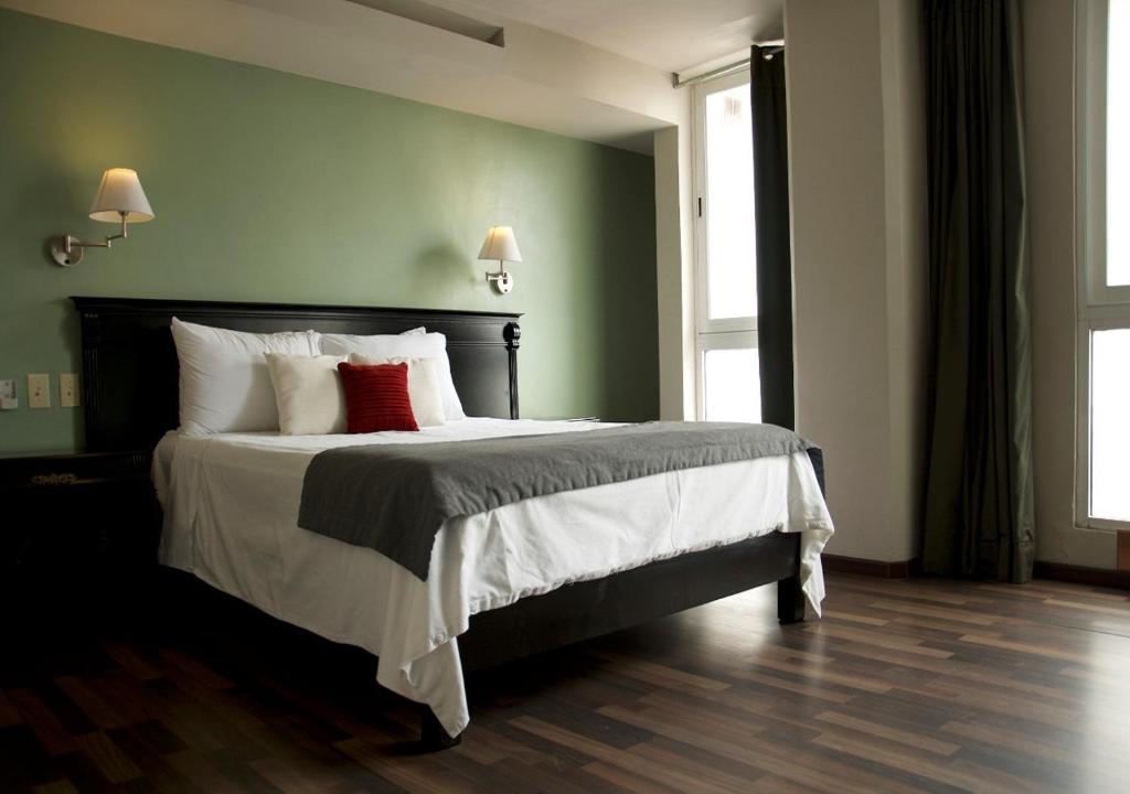 奥里萨巴卢西塔尼亚套房公寓式酒店的一间卧室配有一张大床和两个红色枕头
