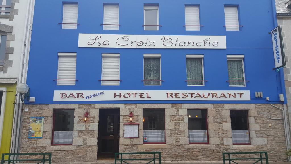 普吕维涅La Croix Blanche的蓝色建筑,上面标有酒吧和酒店餐厅的标志