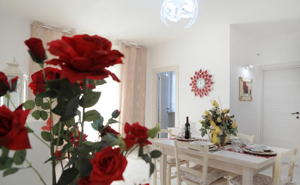 佩兹迪格雷科De Mola Holiday House的一间设有桌子和红玫瑰的用餐室