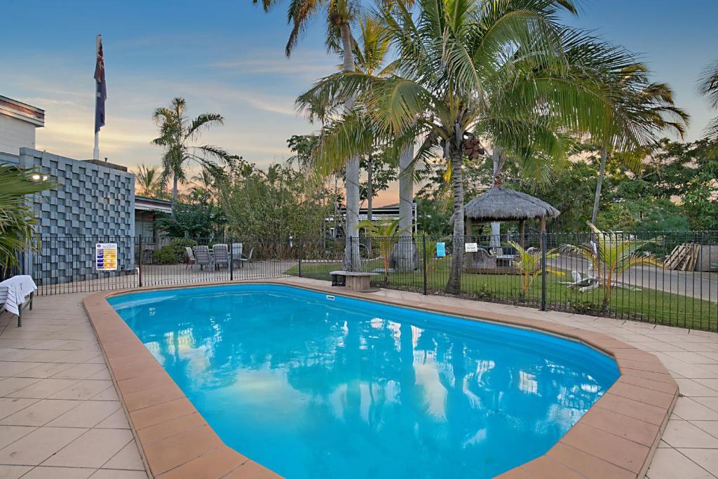 格拉德斯通South Gladstone Motel的棕榈树庭院里的一个大型蓝色游泳池