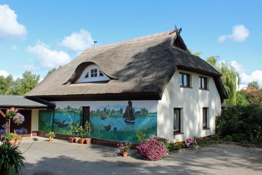 Neuendorf HeideZur Alten Boddenfischerei Ferienwohnung Zander的茅草屋顶的房子,上面有绘画