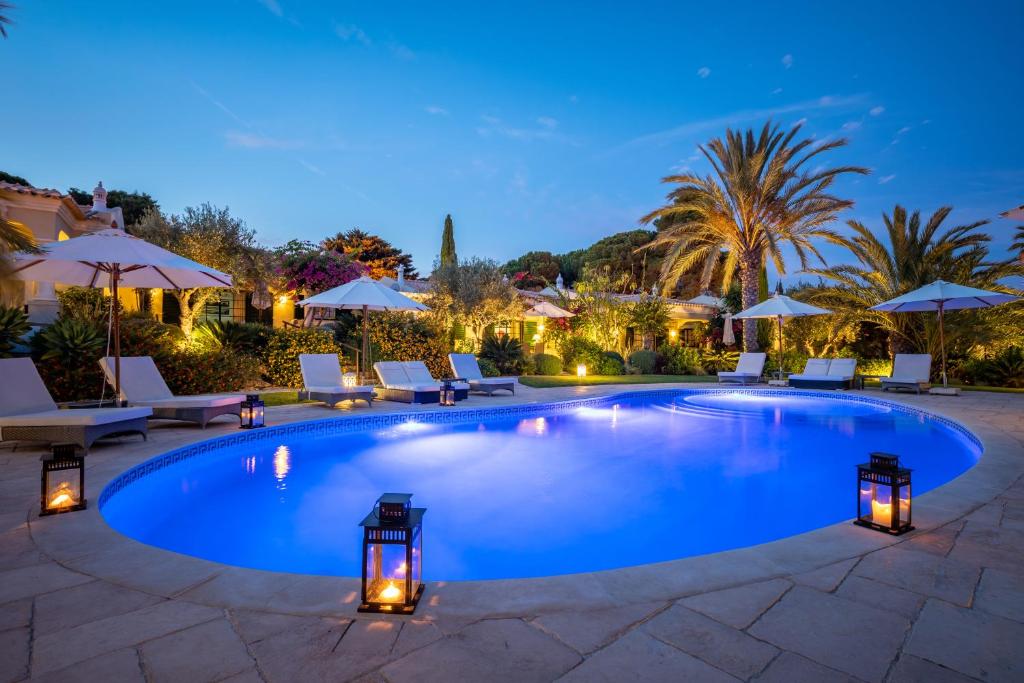 阿尔布费拉Vila Balaia - Luxury Boutique Villas的游泳池在晚上配有椅子和遮阳伞