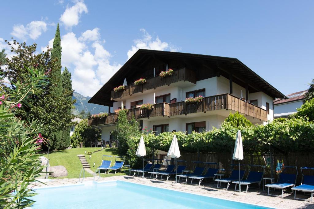 梅拉诺Pension Sankt Urban的游泳池旁的酒店拥有椅子和遮阳伞