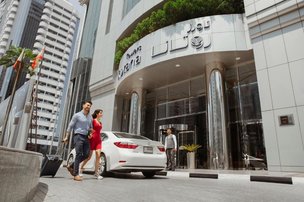 迪拜迪拜罗塔纳大厦酒店的男人和女人在大楼前走过一辆白色汽车