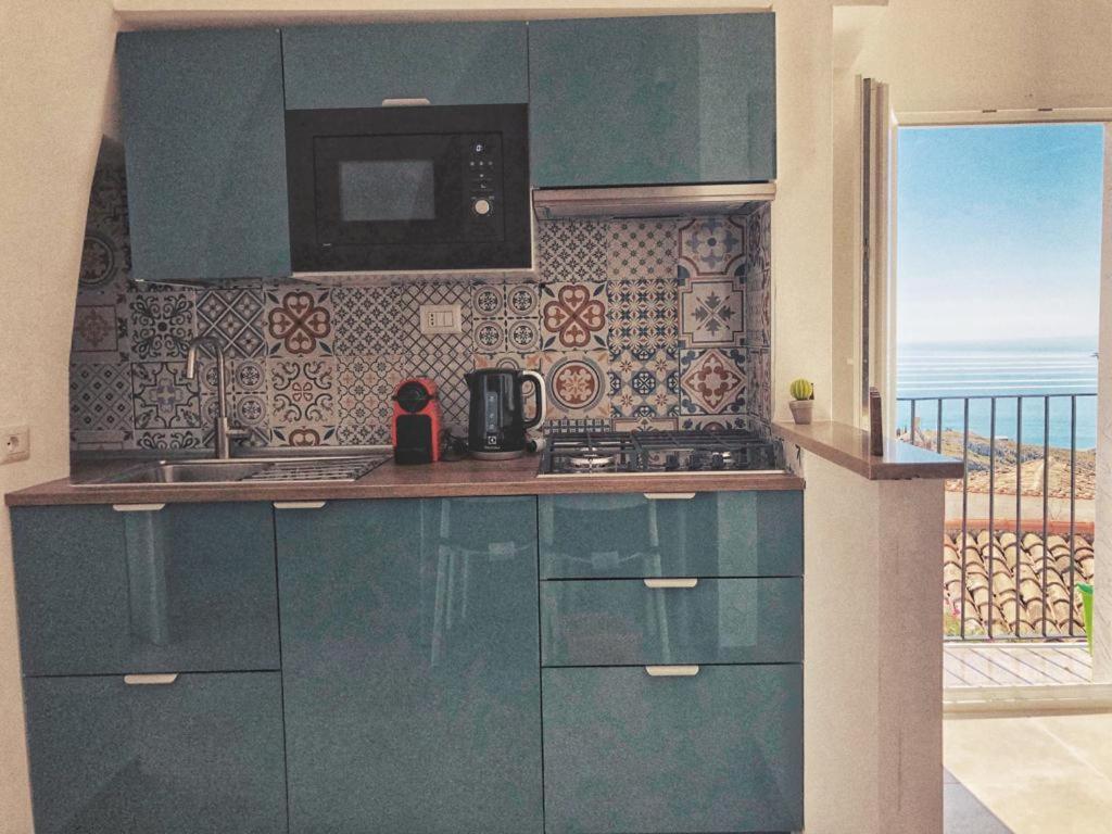 圣安吉罗山Fico d’India apartments的一间设有蓝色橱柜的厨房,享有海景