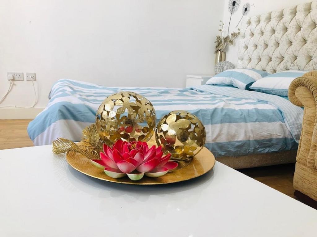 克劳利Lux Apartment in Gatwick的一张桌子上放着花的盘子,放在床边