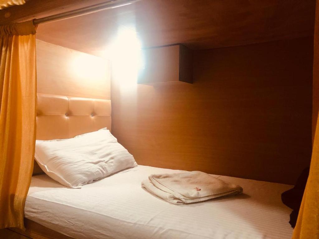 孟买Mabrook Dormitory的一张带木制床头板和白色枕头的床