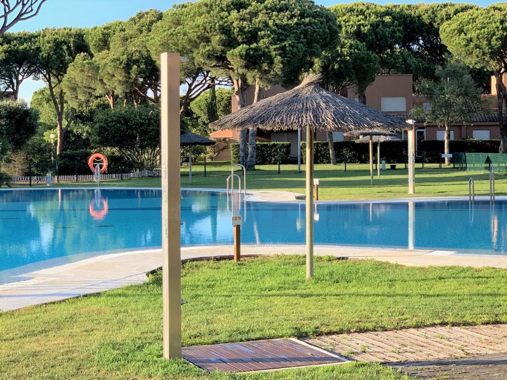 奇克拉纳－德拉弗龙特拉Novo Sancti Petri - Adosado Residencial El Trebol - Chiclana的一个带稻草伞的游泳池的度假酒店