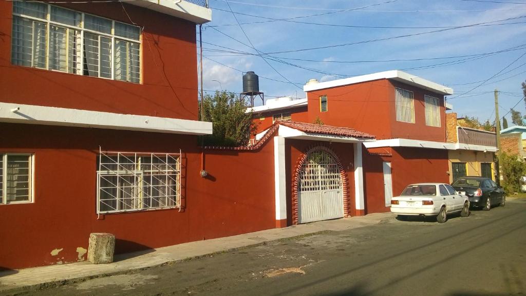 莫雷利亚Casa Celia的一条街道旁的红色建筑,有一辆白色的汽车