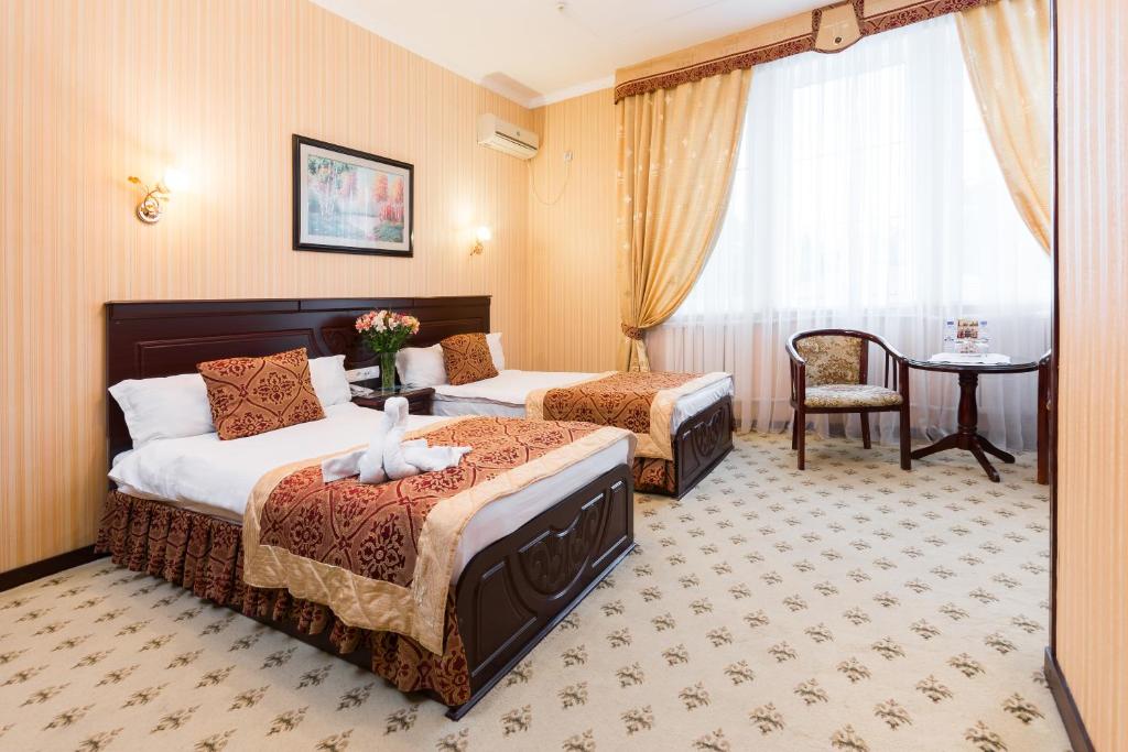 费尔干纳Asia Hotel Fergana的酒店客房设有两张床和一张桌子。