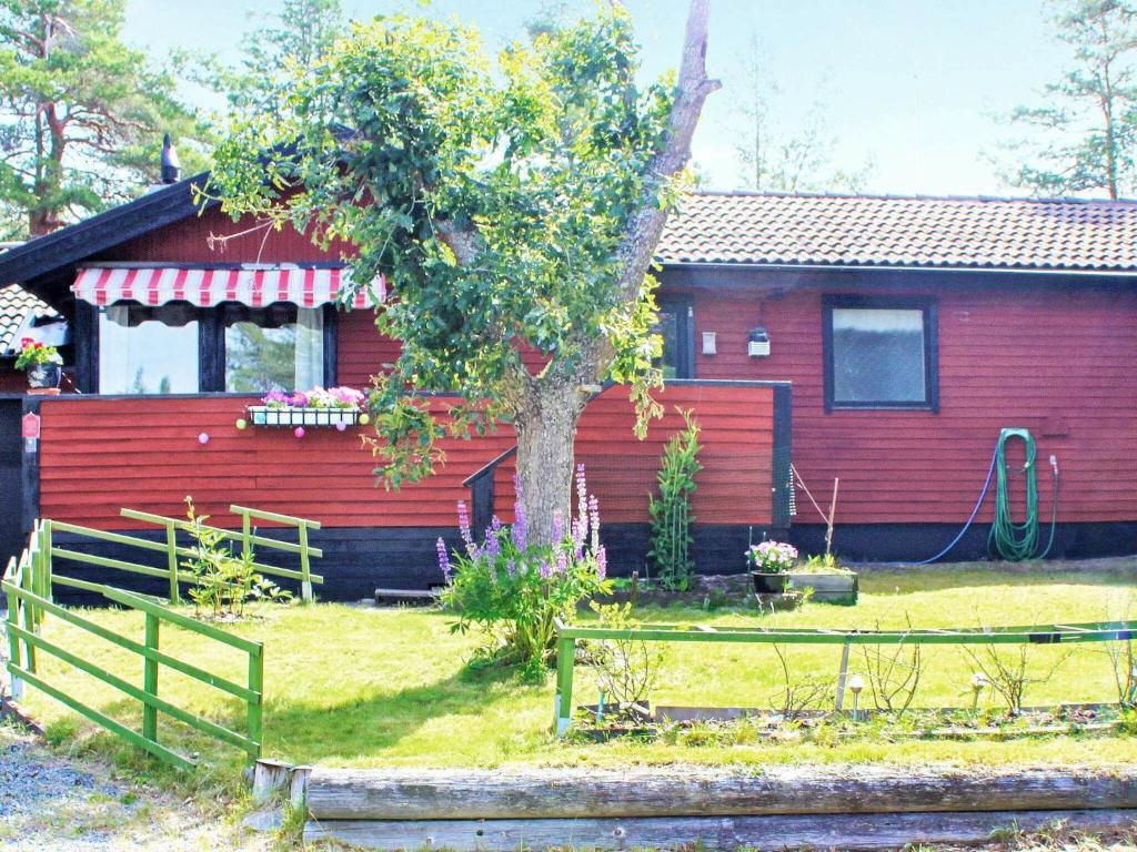 利雪平7 person holiday home in LIDK PING的前面有一棵树的红色房子
