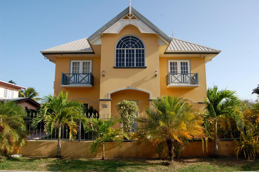 Bon Accord Village卡萨戴尔苏多巴哥别墅的棕榈树前方的黄色房子