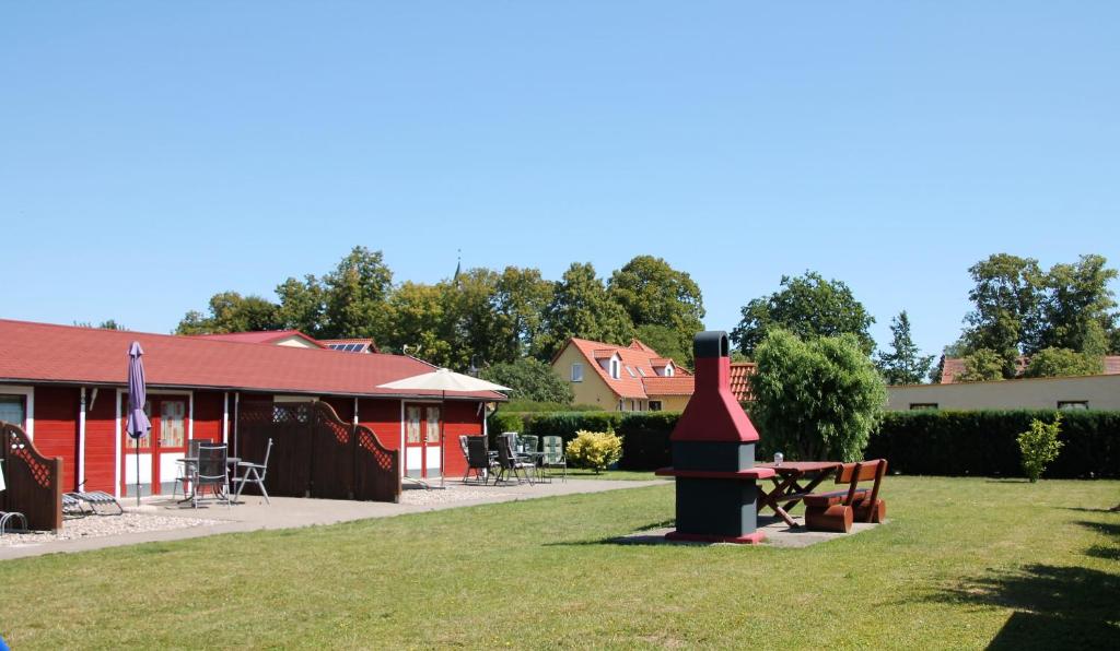 LudorfBlockhäuser an der Müritz的一座红色的建筑,在草地上设有烤架