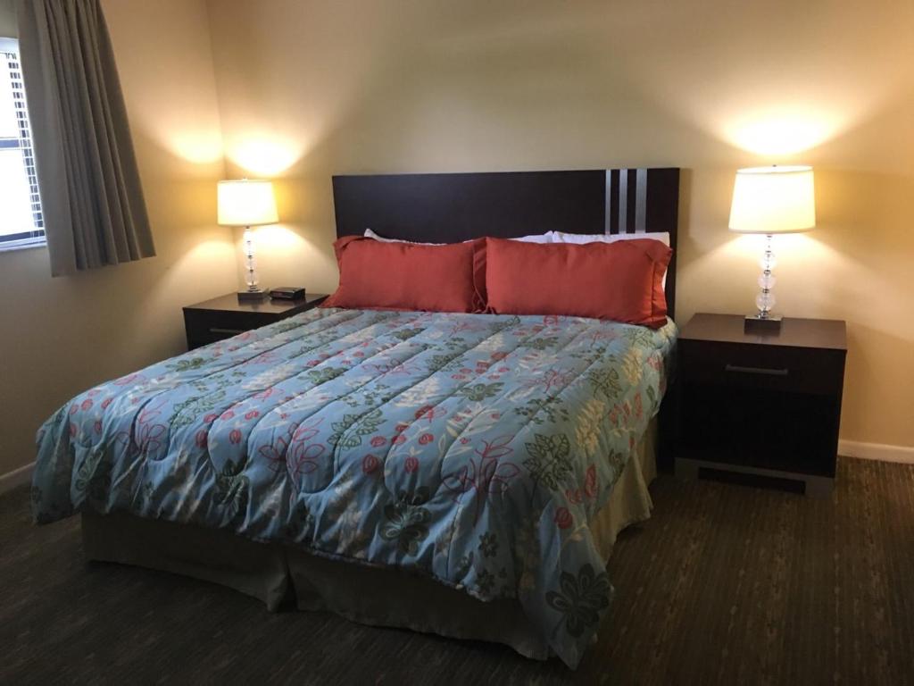 帕诺滩分时冲浪者度假酒店的一间卧室配有一张带红色枕头的床和两盏灯。