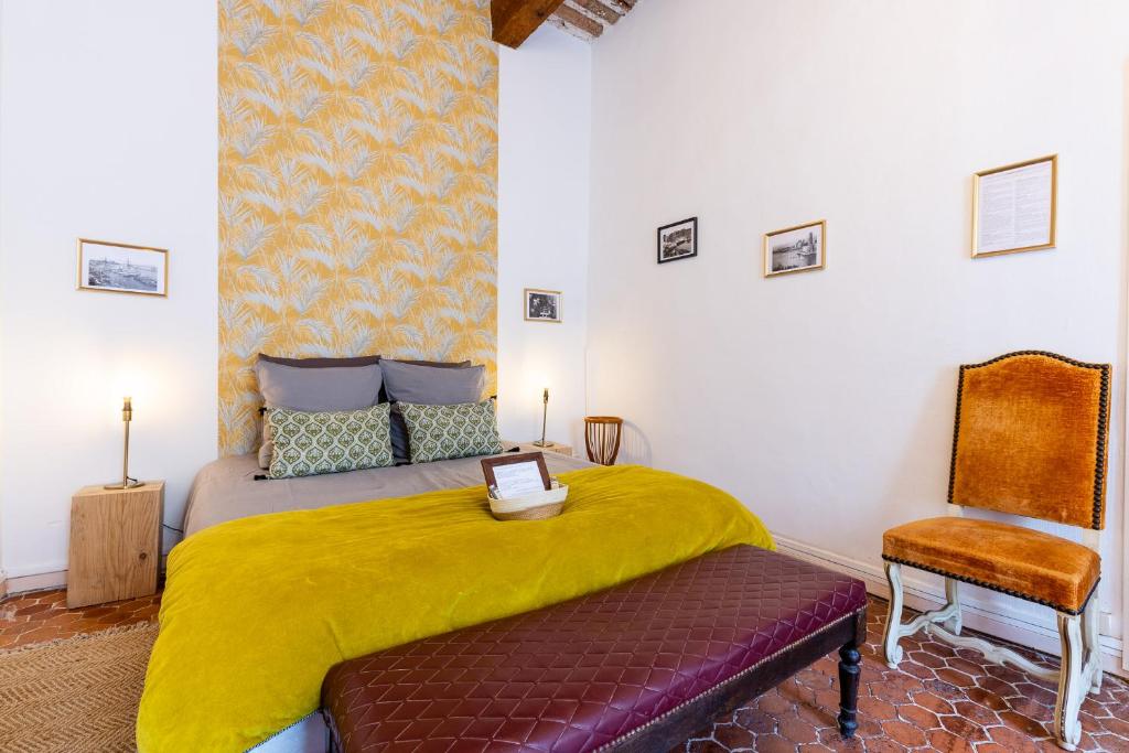 马赛LE PANIER ENCHANTÉ - Suites & Loft - Terrasse et patio au dessus du Vieux Port的一间卧室配有一张带黄毯和椅子的床