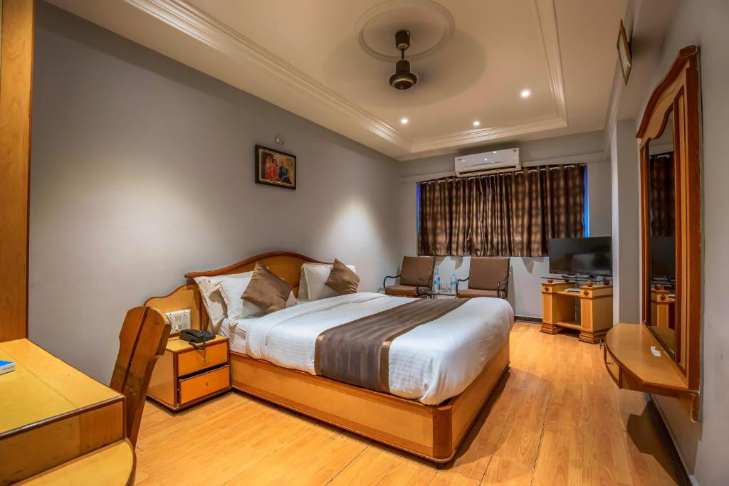 拉杰果德JMC集团酒店的一间卧室配有一张床、一张书桌和一台电视