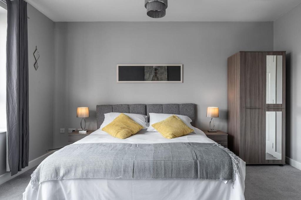 米尔顿凯恩斯Ashland House的白色卧室配有一张带黄色枕头的大床