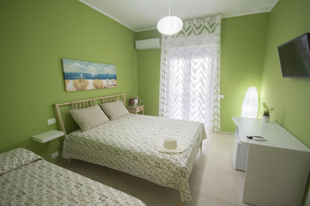 莱西纳Lido Rosa Rooms的绿色卧室设有两张床和窗户