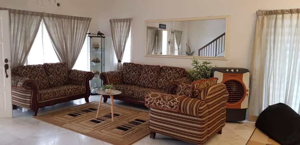 万挠Tun Perak Homestay的客厅配有沙发、椅子和镜子
