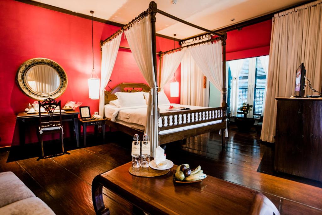 玛琅Hotel Tugu Malang - CHSE Certified的一间卧室配有一张天蓬床和一张桌子及四柱床。