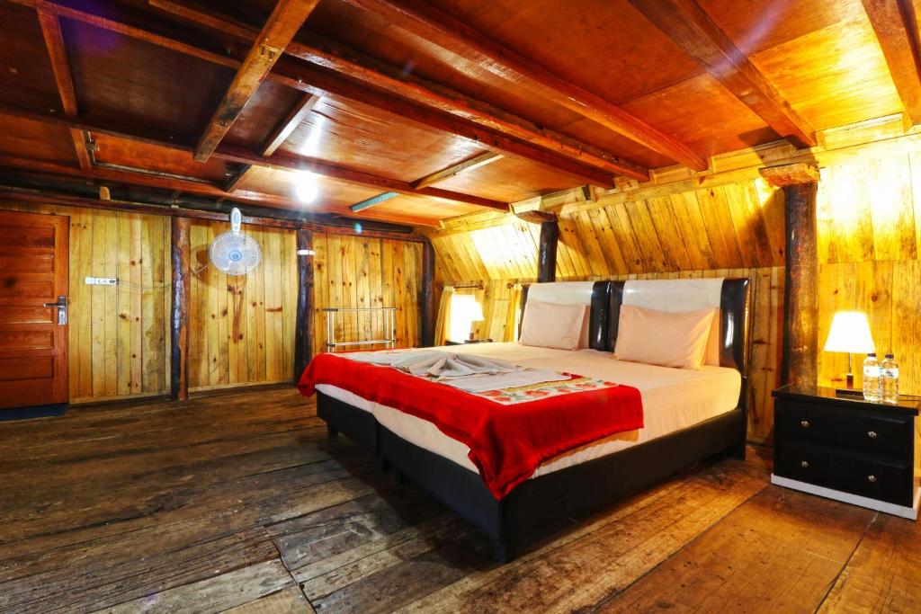 图克图克笃笃提姆布尔简易别墅的卧室配有一张床铺,位于带木墙的房间内