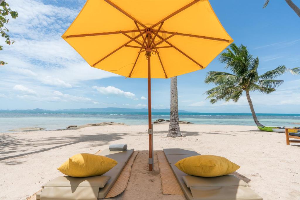 哈林海滩Princess Paradise Koh Phangan的海滩上的黄色遮阳伞和两个枕头