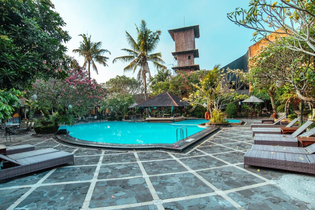 日惹Jogja Village的一个带椅子和塔的度假村游泳池