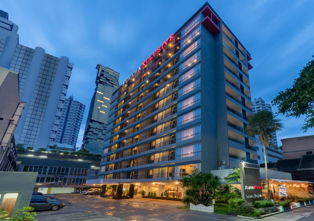 曼谷西隆富丽萨通酒店的一座高大的建筑,城市里灯火通明