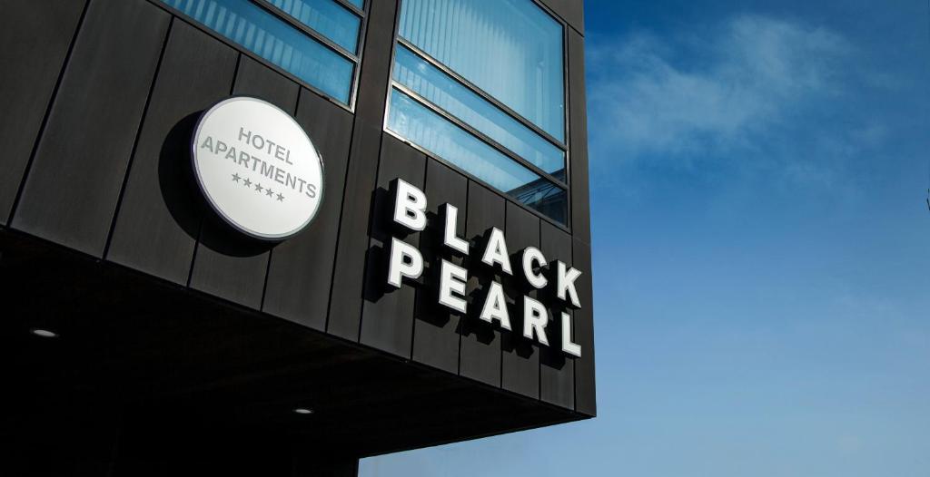 雷克雅未克黑珍珠公寓酒店的黑色的石灰墙建筑的一侧的一个大标志